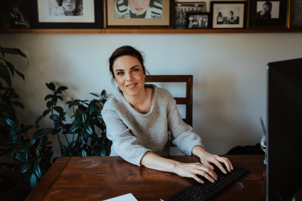 Woman sitting at a wooden desk and working on a computer.