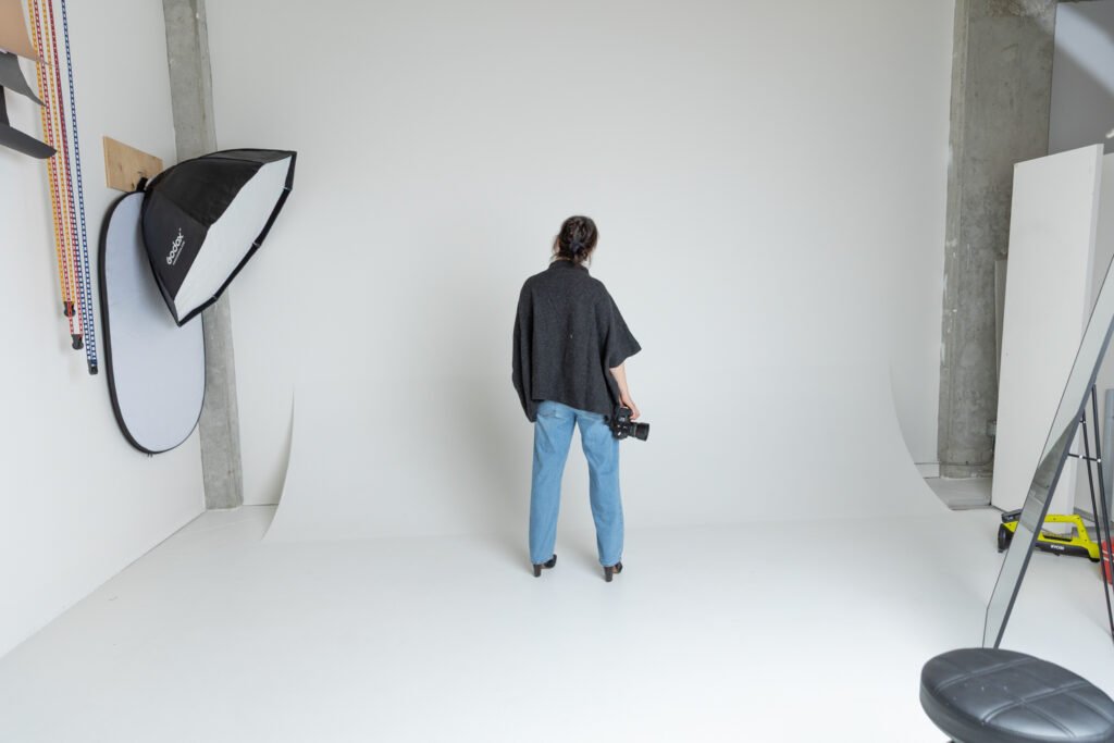 Photographer standing in a studio surrounded by professional photography equipment